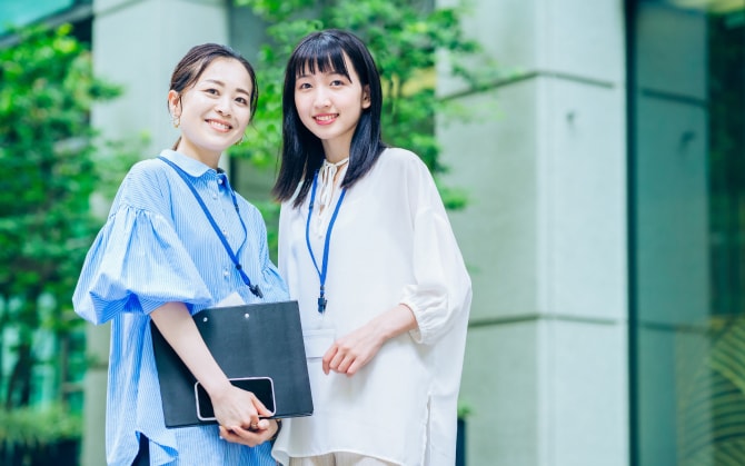 勤務中の女性二人がこちらを見て微笑む様子